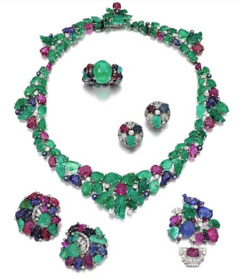 A gem-set and diamond wreath of carved rubies, emeralds and sapphires in the Art Deco ‘ Tutti Frutti’ style, with related clips, earrings and a ring. Estimate £40,000 to £60,000.